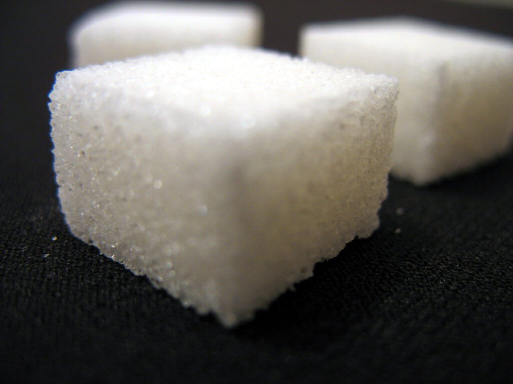 Photograph of three sugar cubes on a black surface.