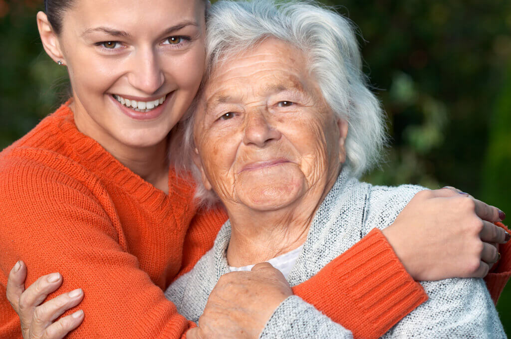 Younger woman hugging an older woman, possibly her mother or grandmother.