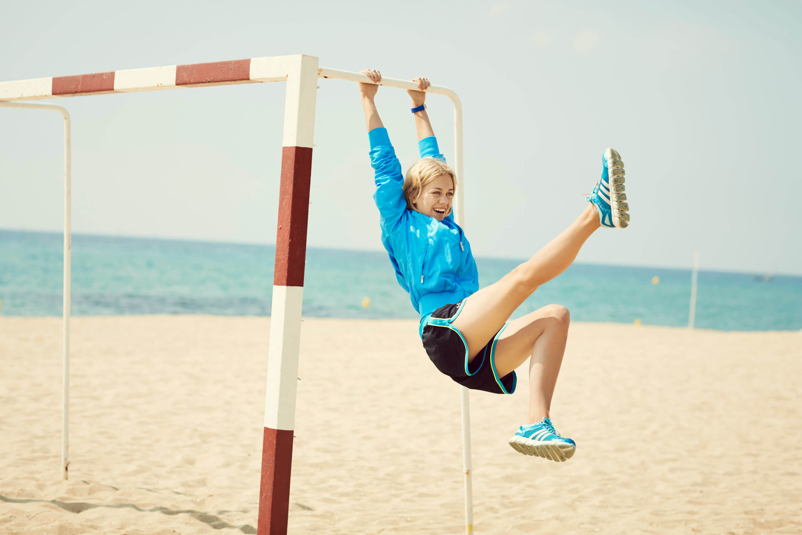 Blonde woman swinging on a bar at the beach.