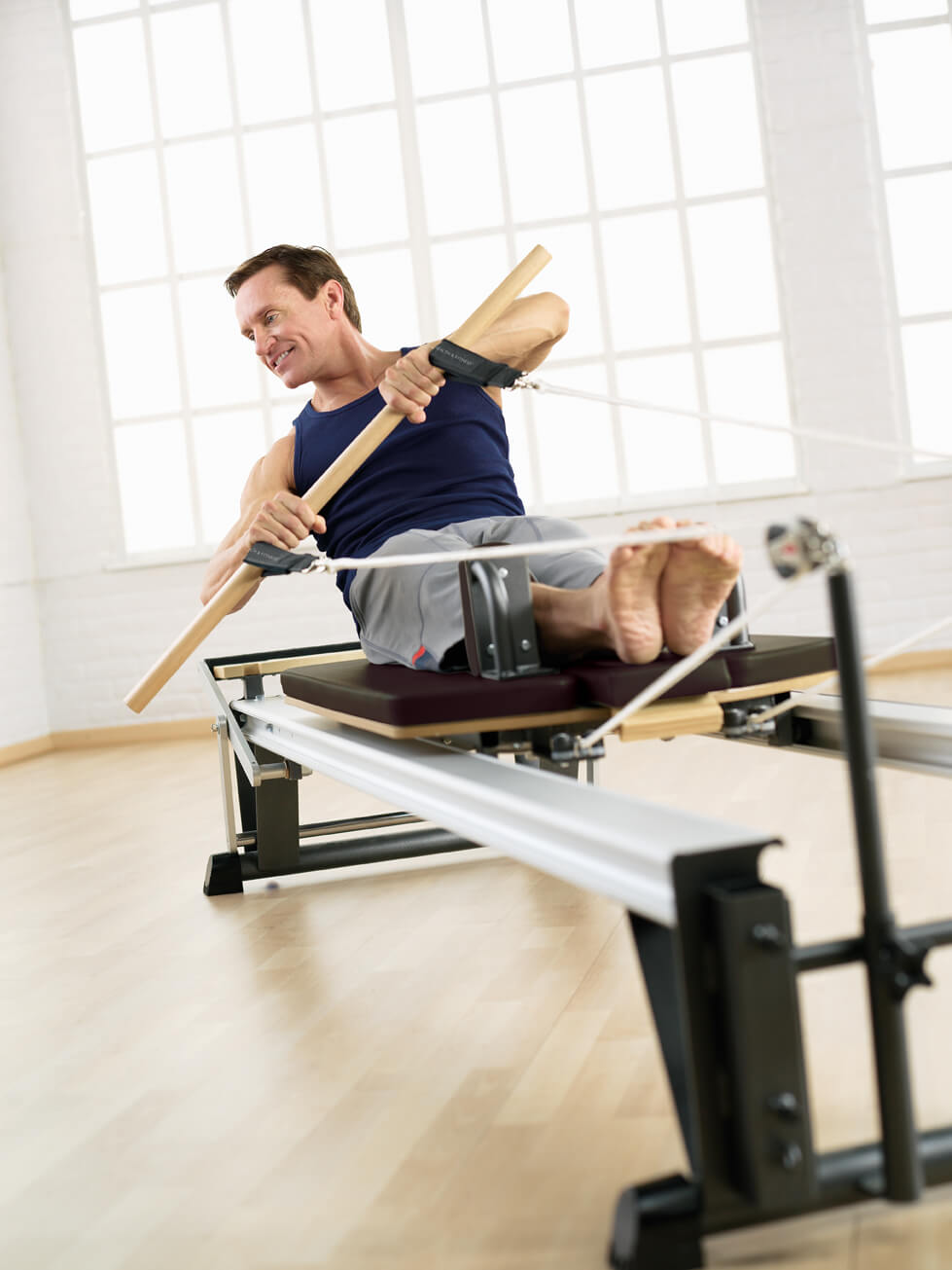 Man doing rowing exercises on a reformer machine.