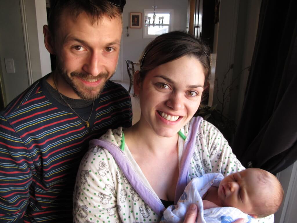 Brand new parents, a man and a woman, show off their baby.