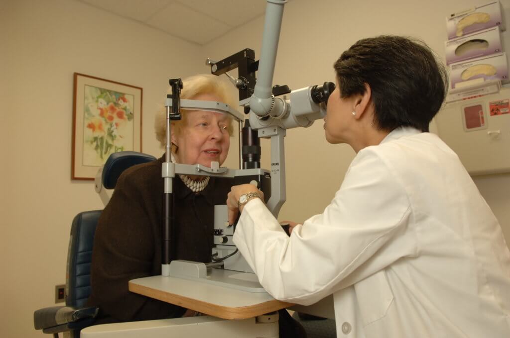 Elderly woman having her eyes examined by a younger female optometrist.