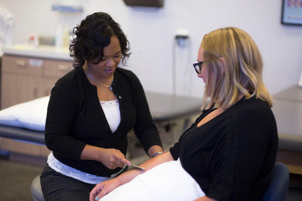 Female physical therapist works the tissue of a female patient's right arm to reduce tension in the muscle and tissue.