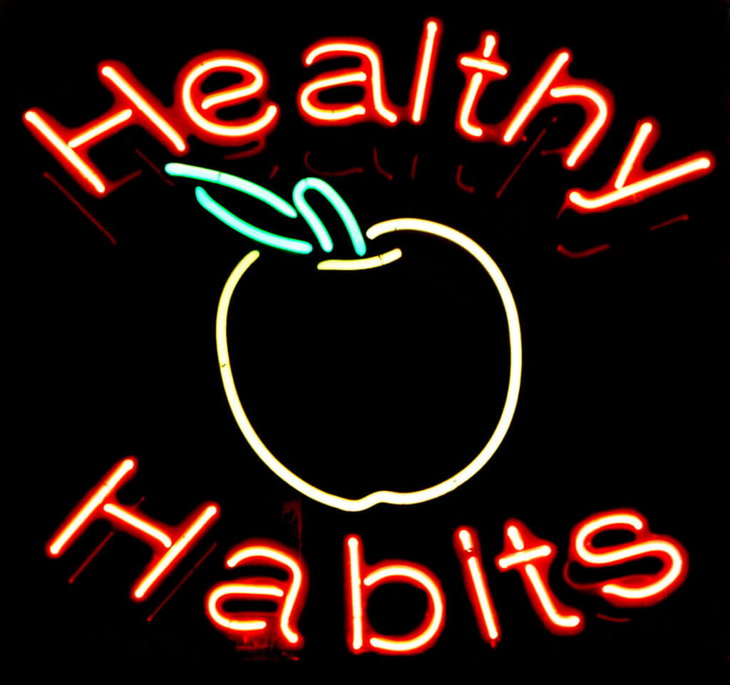 Neon sign that says "Healthy Habits" with an image of an apple.